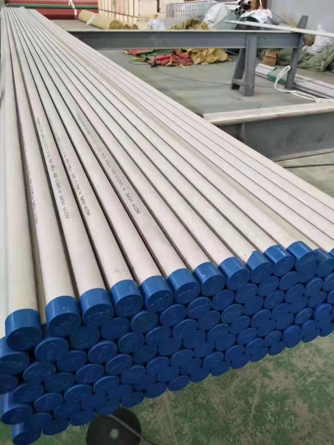 matte gray AP stainless steel tubes stacked in an industrial warehouse